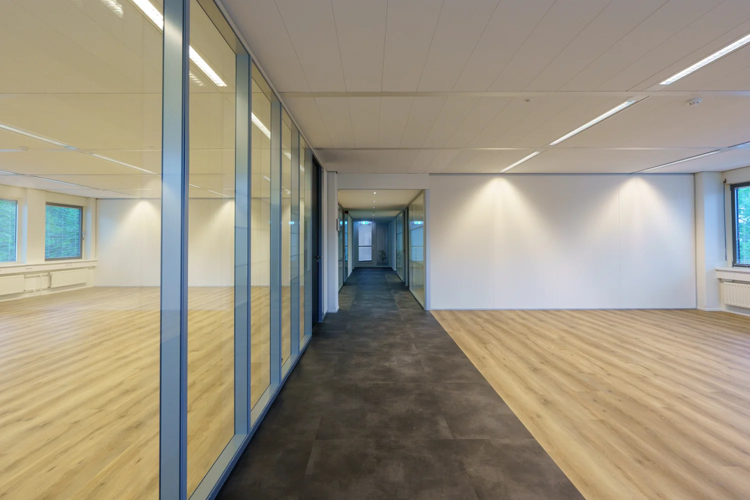 Moderne, lege kantoorruimte aan de Baarnsche Dijk met glazen wanden en houten vloer.